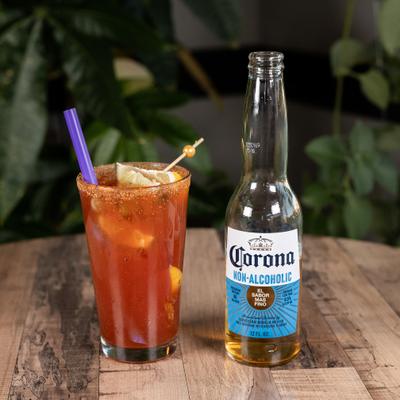 Michelada in a chili-rimmed glass, beside a bottle of beer.