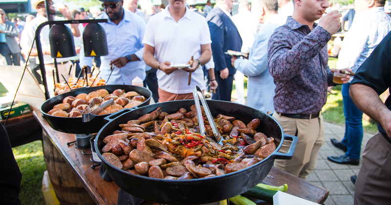 Staff member cooking sausages in huge pan