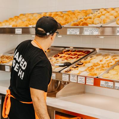 A person putting baked goods on display.