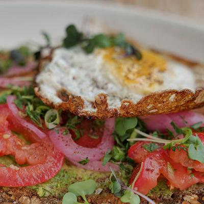 Avocado toast with pickled red onion, tomato, micro herbs and fried egg