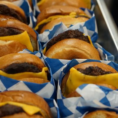 Tray of cheeseburgers  served in blue and white checkered wrappers.