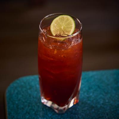 Thai Iced Tea served in a highball and garnished with a lime wheel.