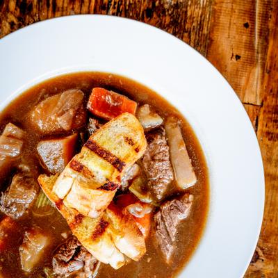 A serving of beef stew on a wooden table.