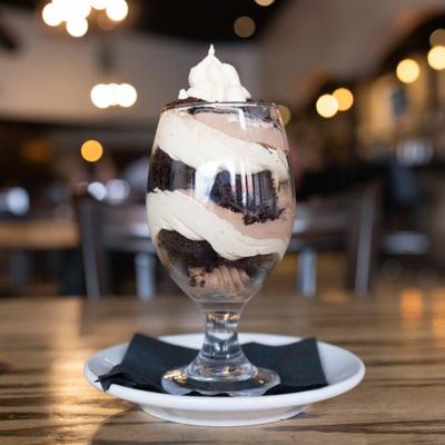 Peanut butter and chocolate dessert with whipped cream served in a glass.