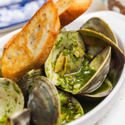 Clams in a green sauce with crostini, close up.
