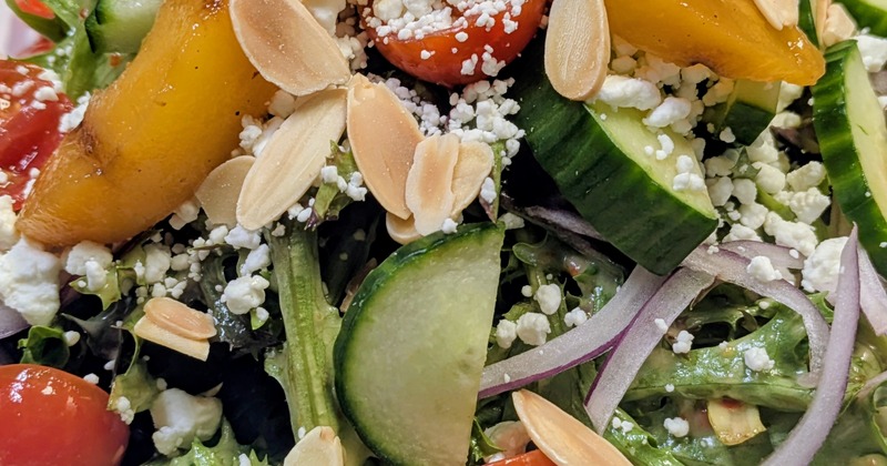 House salad topped with grilled peaches, cheese crumbles and almonds