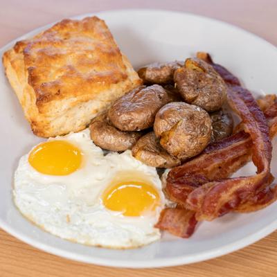 American breakfast with eggs, bacon, potatoes, and biscuit.
