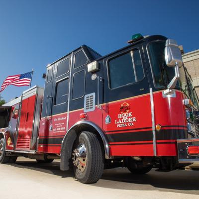 Hook and Ladder Pizza Co fire truck promotional vehicle parked with an American flag.