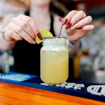A bartender garnishes a drink with a lime wedge.