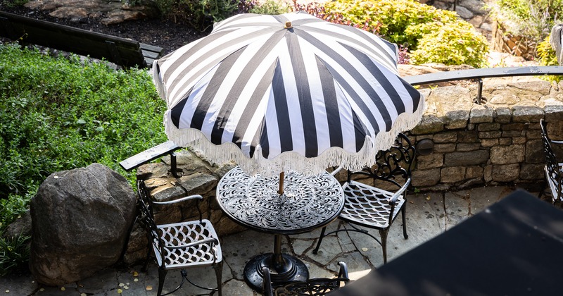 Patio with an ornate metal table for two guests and a black-and-white striped umbrella