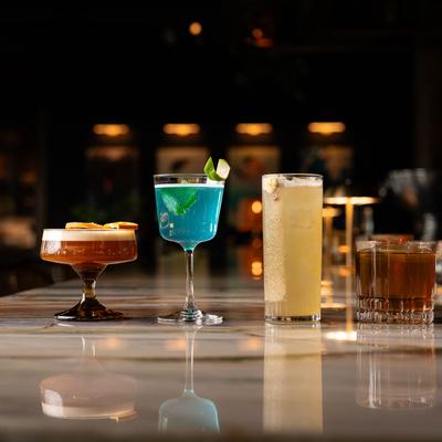 A row of four cocktails on a marble bar.