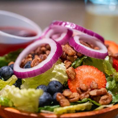 Summer salad with lettuce, blueberries, strawberries, pecans, and red onions.
