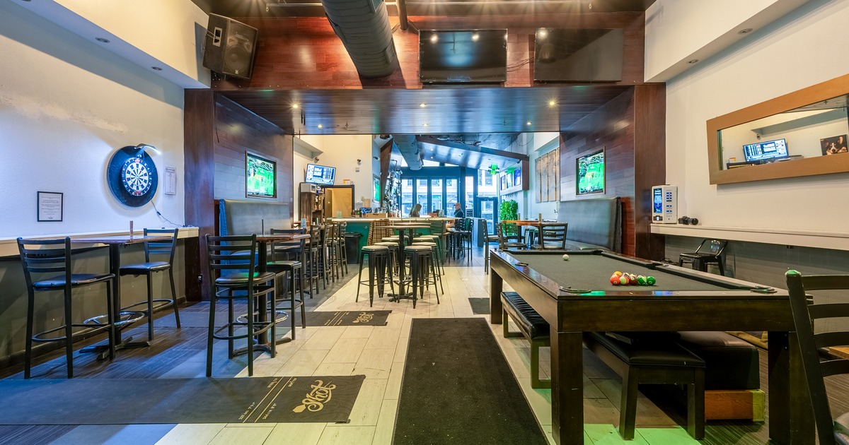 Interior of a sports bar with bar stools and high tables and a pool table on the right side