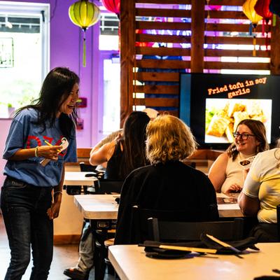 A restaurant scene showing people dining under lanterns with a tofu presentation.