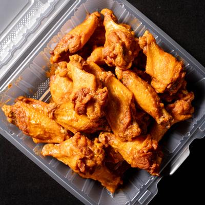 Buffalo chicken wings served in a plastic container.