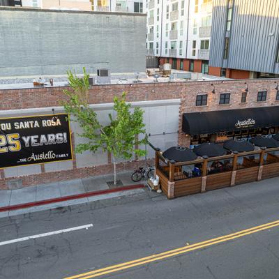 Restaurant exterior with outdoor seating and large wall banner.