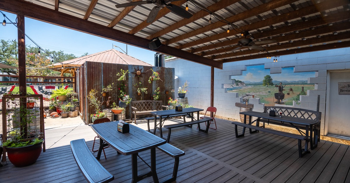 Covered patio with wooden beams and fans, featuring black picnic tables
