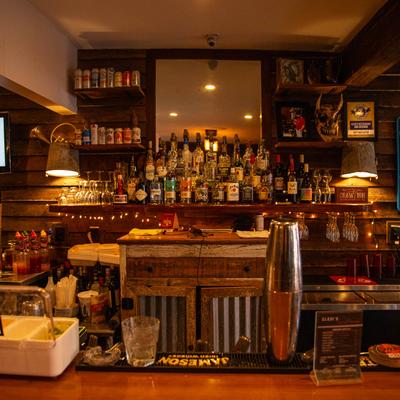 Bar area, various liquor bottles, cans, and glasses.