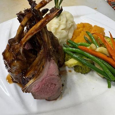 Rack of lamb served with mashed potatoes, mashed sweet potatoes and vegetables.