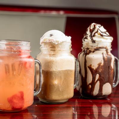 Various drinks served in traditional glass mason jar mugs.