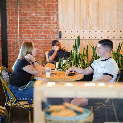 Several people sit at tables inside a busy brick cafe.