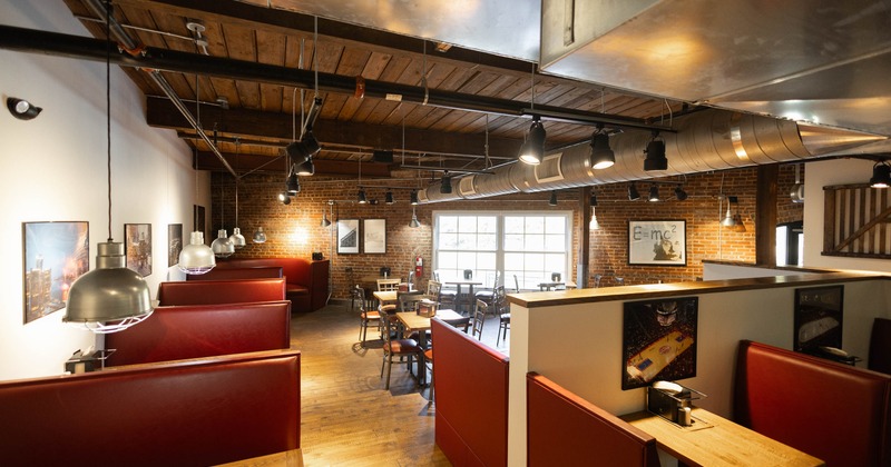 Interior of a restaurant with red booths, and wooden tables