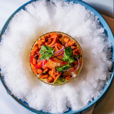 Chilled fruit and nut salad in a glass bowl over crushed ice.