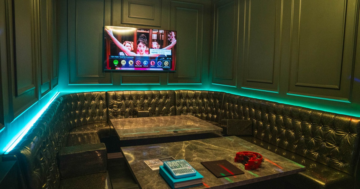 Interior, button tufted leather seating by a wall with tables, TV on the wall