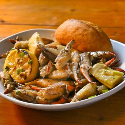 Crab claws served with a bread roll and grilled lemon half.