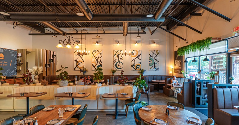Interior, dining room, abstract wall art, plants, booths, and set dining tables