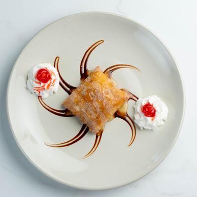 Sopapilla dessert with whipped cream and maraschino cherries.