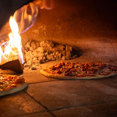 Pizzas being cooked inside a wood-fired oven.