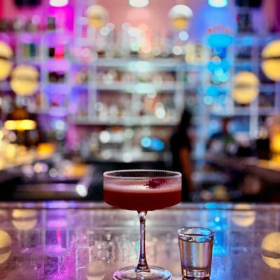 A cocktail porn star calle dragones on the countertop of the bar, with bottles and lights in the back.