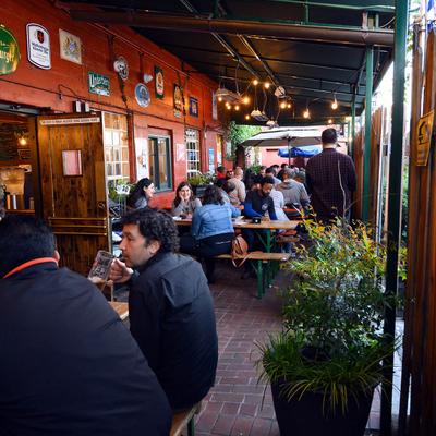 Covered patio, seating area, customers having drinks.
