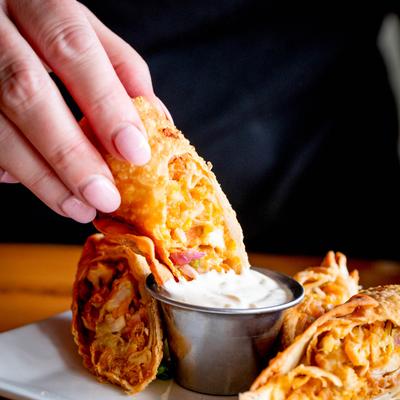 Egg roll dipped into a cup of sauce.