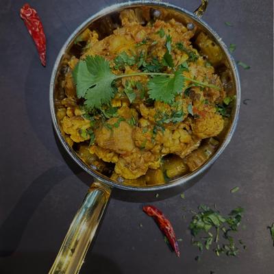 Vegetable curry disdh served in a pan, garnished with fresh cilantro.