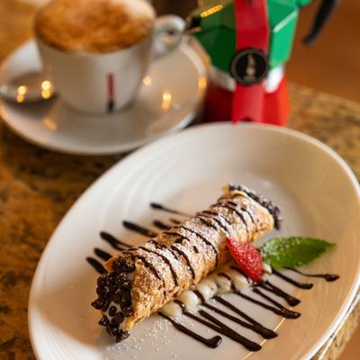 Cannoli garnished with chocolate chips, chocolate sauce drizzle and a strawberry slice.
