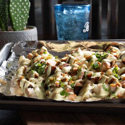 Baked potato, smothered in gouda cheese, with chicken, scallions, and cilantro garlic drizzle.