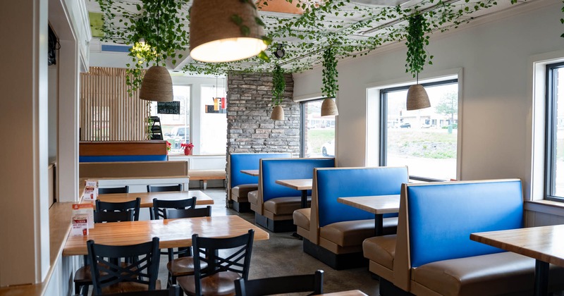 Interior, seating booths padded in blue leather, tables for four, large windows, stone wall