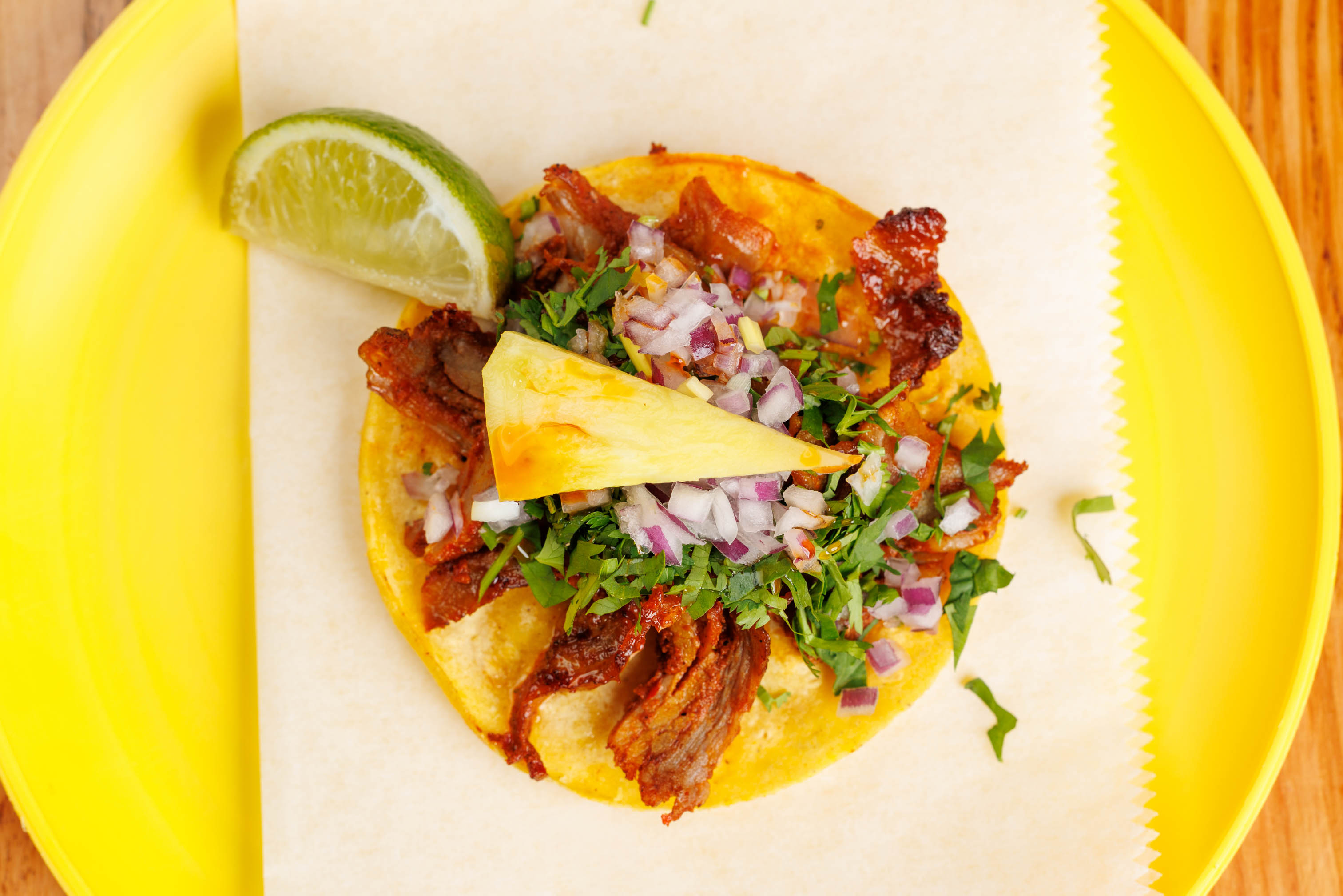 Del Trompo taco, topped with a pineapple slice and a lime wedge