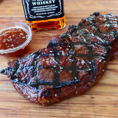 Grilled and glazed sirloin steak, with spicy sauce, and a bottle of whiskey.