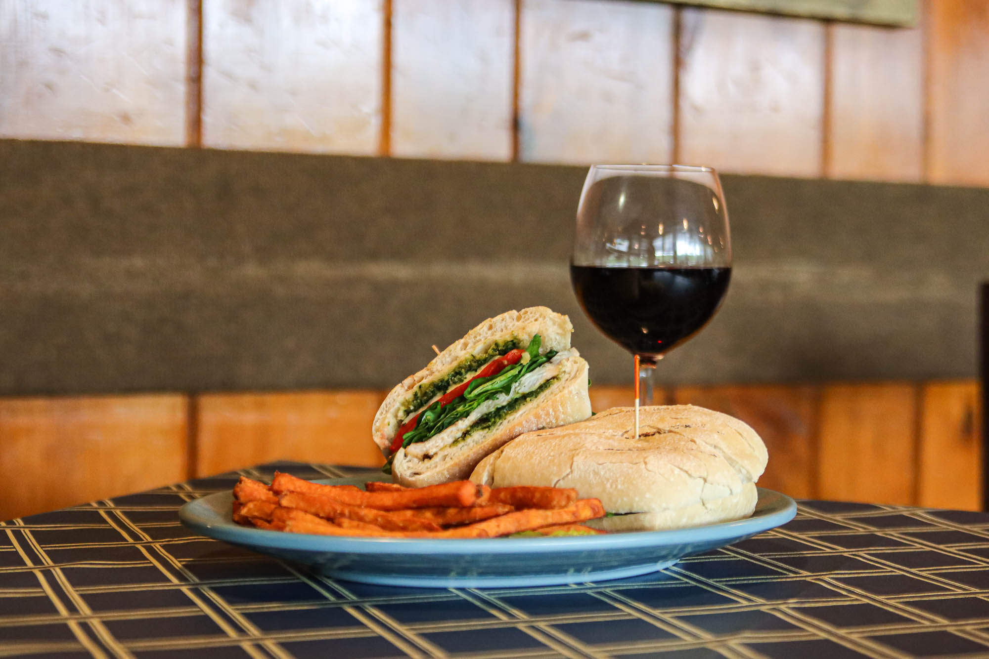 Grilled Chicken Pesto Sandwich with a side of sweet potato fries and a glass of red wine