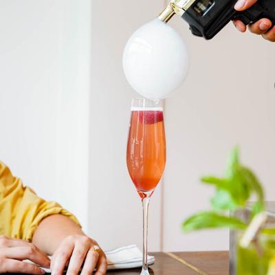 Beso cocktail, an employee finishing the cocktail with the smoke bubble gun.