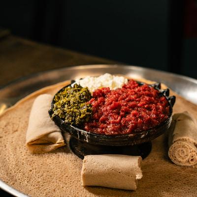 Minced raw beef served with traditional cheese, cooked greens, and injera flatbread.