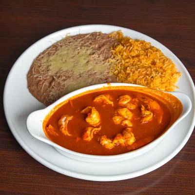 Bowl of shrimp in a spicy red sauce served with seasoned rice and refried beans.