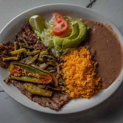 Grilled steak, with pepper, rice, beans, salad, and avocado.