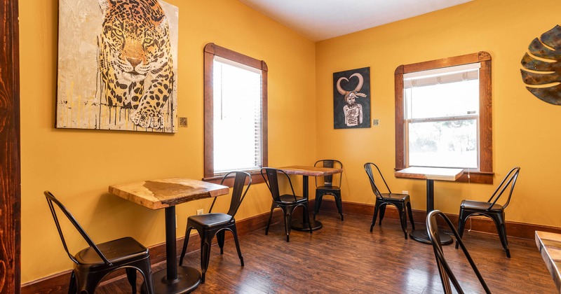 Interior, tables for two, large leopard painting, walls painted in yellow, windows