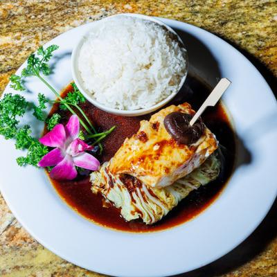 Grilled fish served with white rice, savory sauce, and orchid.