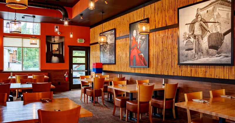 Interior of a restaurant featuring orange walls, bamboo textures, wooden tables