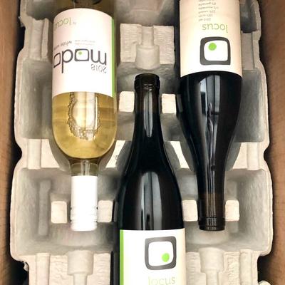 Three bottles of wine neatly arranged in a cardboard box, top view.